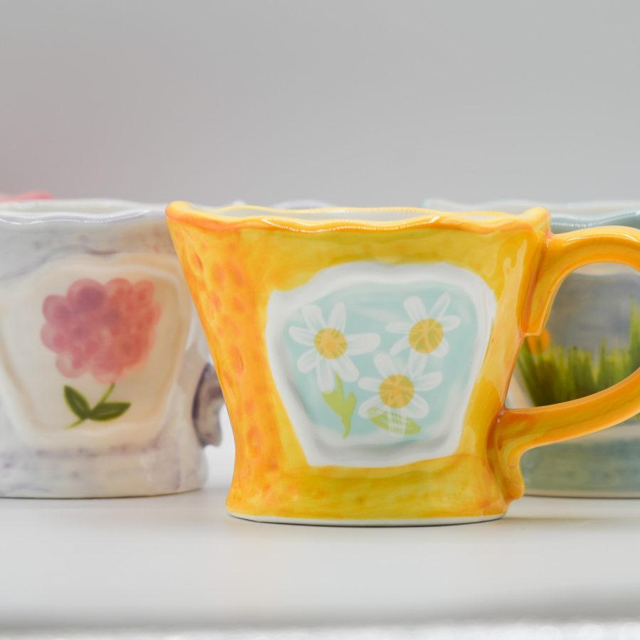Colorful ceramic mugs with hand-painted floral designs, showcasing a cozy aesthetic