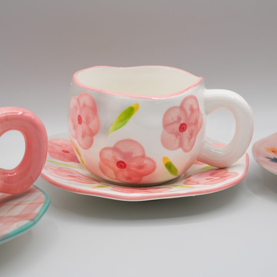 Set of decorative ceramic cups with matching saucers in floral and plaid patterns, perfect for tea or coffee.