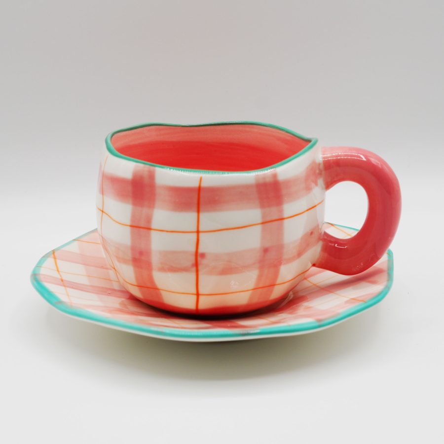 Plaid ceramic cup and saucer set in pink and white with green rim – perfect for tea or coffee.