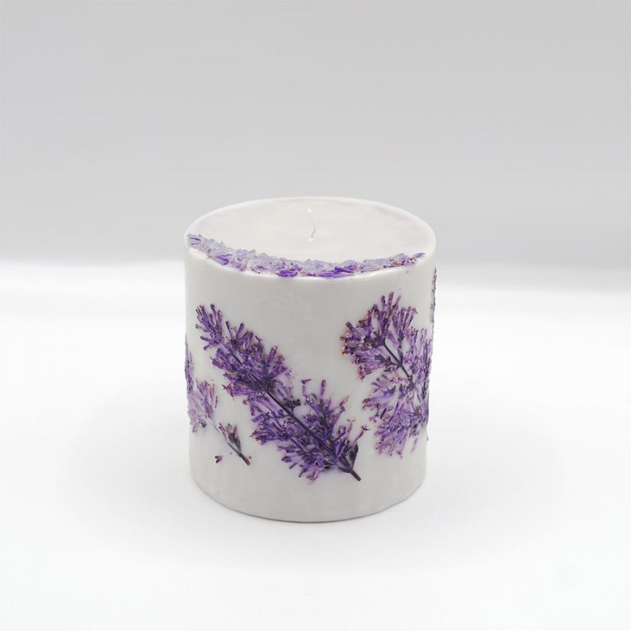Handcrafted lilac botanical candle scented with basil and lavender on a white background.