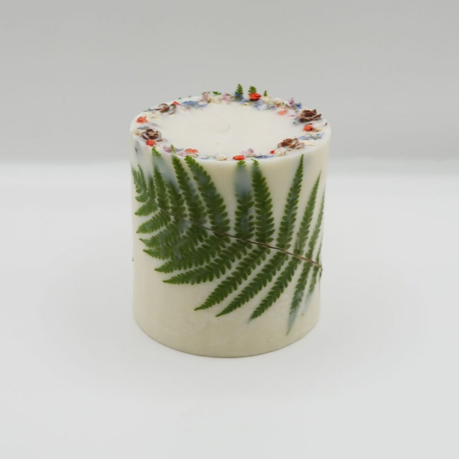 Handcrafted green botanical candle scented with passion fruit on a white background.
