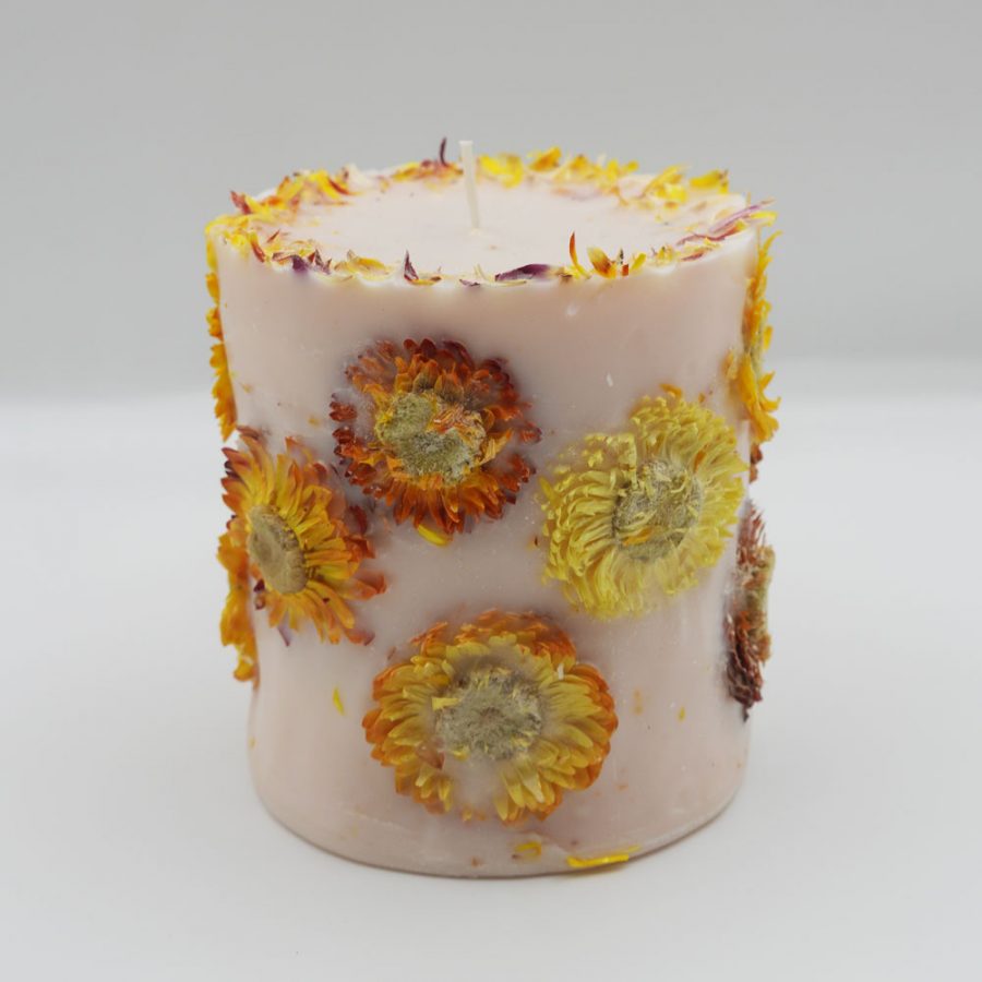 Handcrafted yellow botanical candle scented with orange and lemongrass on a white background