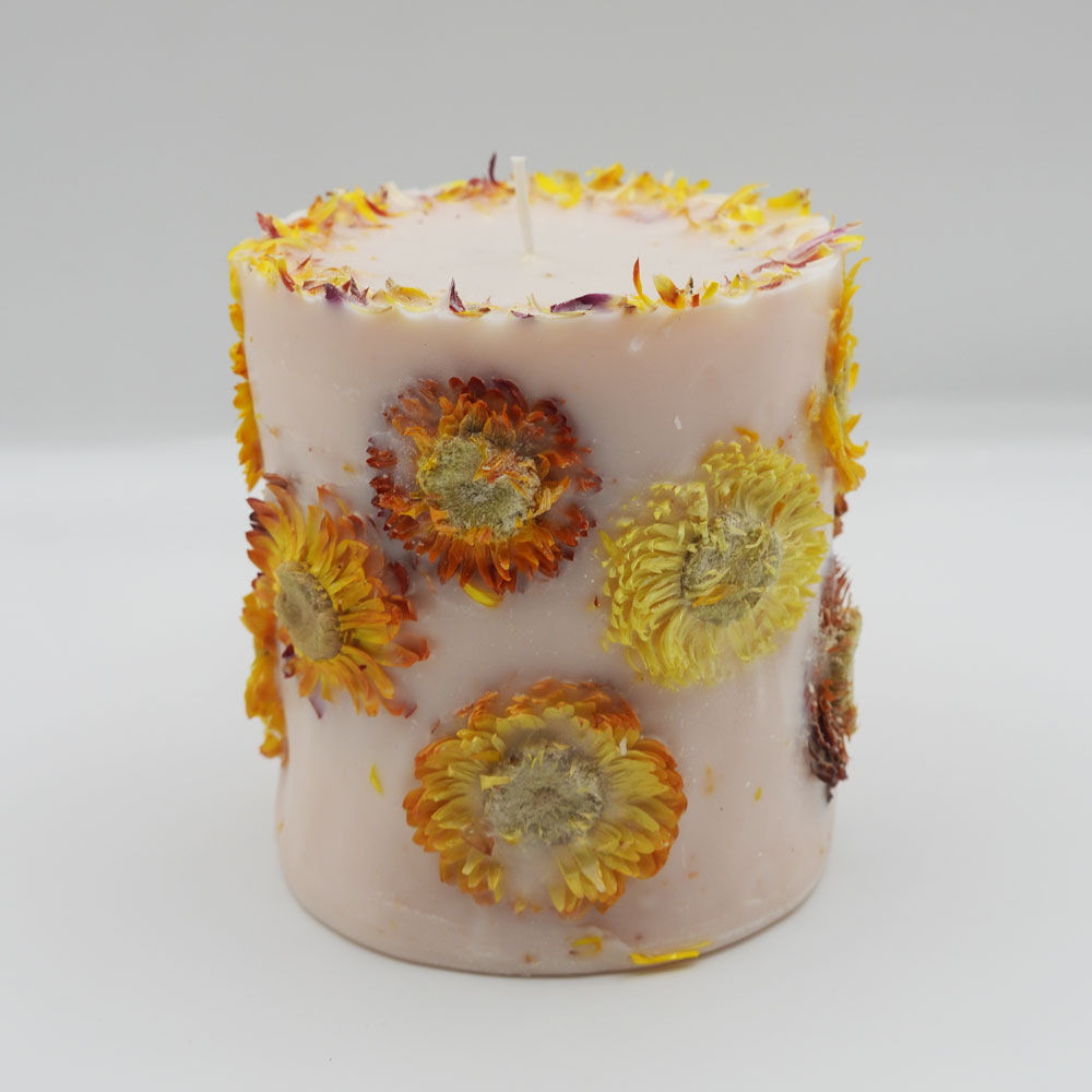 Handcrafted yellow botanical candle scented with orange and lemongrass on a white background